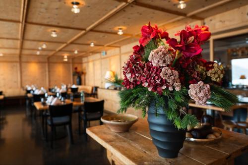 a vase of flowers on a table in a restaurant at Hotel Stoffel - adults only in Arosa
