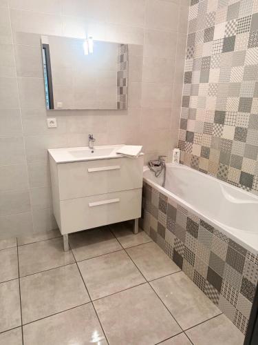 une salle de bain avec un lavabo, une baignoire et un miroir dans l'établissement T2 étage Lumineux à Leyment, à Leyment