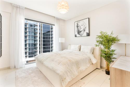 a white bedroom with a bed and a window at Luxury 2BR in Sobha Hartland in Dubai