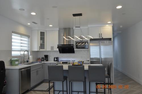 a kitchen with white cabinets and a island with bar stools at Dimond Abode Vacation Home #2 Oakland Dimond District in Oakland