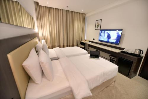 a hotel room with a bed and a television at Carlton Tower Hotel Kuwait in Kuwait