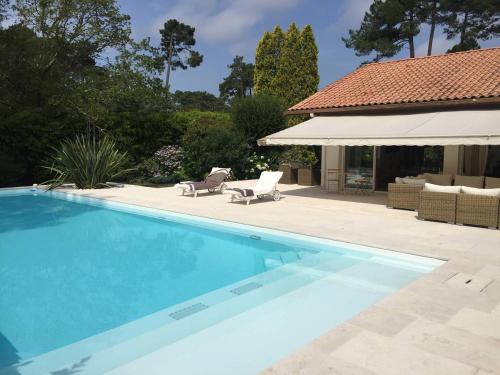 - une piscine avec une terrasse et une maison dans l'établissement Villa BARADARENA avec piscine chauffée et jardin pour 10 personnes, à Hossegor
