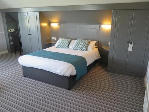 a bedroom with a large bed with blue pillows at Oyster Fleet Hotel in Canvey Island