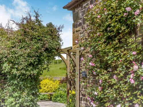 a garden with a wooden gate and flowers at Robin's Nest in Craven Arms