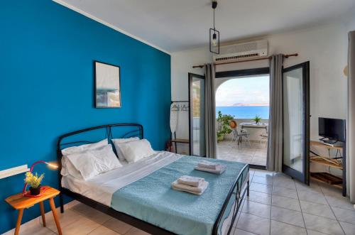 a blue bedroom with a bed and a view of the ocean at Beachfront Blue Comfort Sitia By ComfortBnb in Sitia