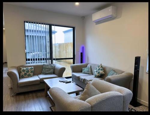 a living room with two couches and a coffee table at Cozy Room in Papakura Auckland in Auckland