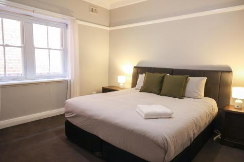 a bedroom with a large bed with two windows at Charm and Value in Central in Wagga Wagga