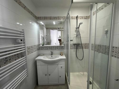 une salle de bain blanche avec une douche et un lavabo dans l'établissement Charmante maison rénovée près du centre - FR-1-709-91, à Fouras
