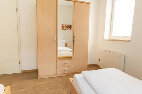 a bedroom with a wooden cabinet with a mirror at Feriendorf Slawitsch in Bad Sulza
