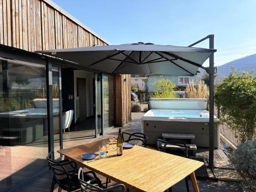 a patio with a table and an umbrella and a hot tub at Sweet Escape et Spa in Turckheim