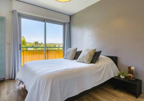une chambre avec un lit blanc avec une grande fenêtre dans l'établissement Appart 2 ch Vue Mer & Montagne, Terrasse, Parking, à Antibes