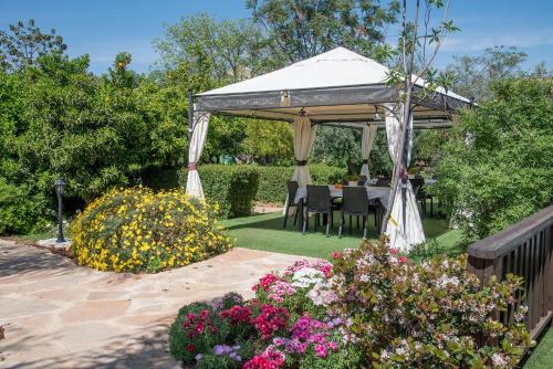 a gazebo with a table and chairs in a garden at Song of Galilee in Elifelet