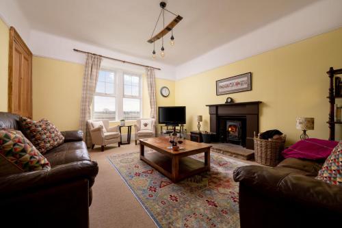 a living room with two couches and a fireplace at Old Duffus Farmhouse in Duffus
