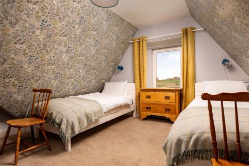 a bedroom with two beds and a window at Old Duffus Farmhouse in Duffus