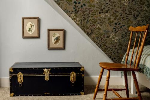 a black trunk sitting next to a chair and a staircase at Old Duffus Farmhouse in Duffus