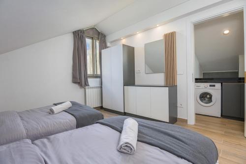 a bedroom with two beds and a kitchen with a washing machine at Winter Light Kfardebian in Kfardebian