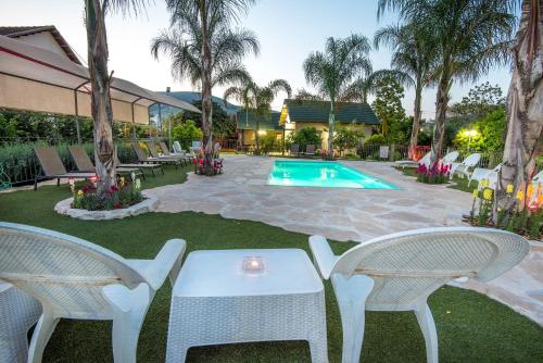 a patio with white chairs and a swimming pool at Song of Galilee in Elifelet