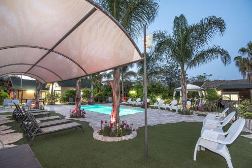 a pool with white chairs and a large umbrella at Song of Galilee in Elifelet