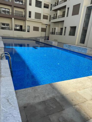 a large blue swimming pool in front of a building at Évasion zen près de Casablanca - Vue imprenable sur le parc et la plage de l'Éco City Zenata in Aïn Harrouda