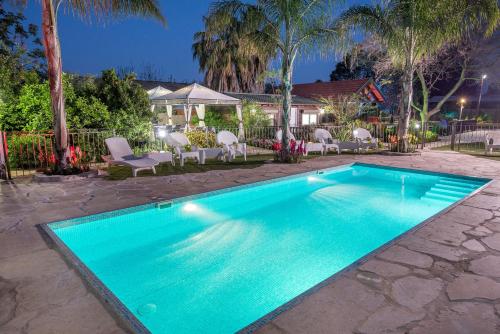 a blue swimming pool with chairs and a house at Song of Galilee in Elifelet