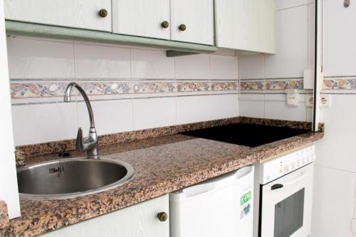 kuchnia ze zlewem i białymi szafkami w obiekcie Apartamentos Topacio Unitursa w mieście Calpe