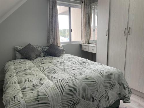 a bedroom with a bed with a black and white comforter at 2 bedroom Apartment on the Bay in Richards Bay