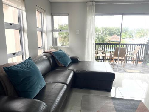 a black leather couch in a living room with a balcony at 2 bedroom Apartment on the Bay in Richards Bay