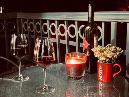 three wine glasses sitting on a table with a bottle of wine at Apartman Miletic in Ostrovo