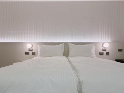 a bedroom with two beds with white sheets and two lamps at 在家行旅 南西館 in Taipei