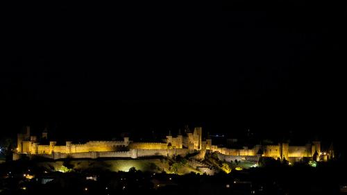 a large castle is lit up at night at L'Atelier B&B - Esprit bohème, la nature en ville in Carcassonne