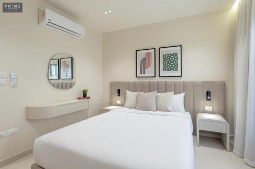 a white bedroom with a large bed and a tub at Prime Residence Zayed Heights in Sheikh Zayed