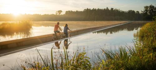 two people riding bikes on a bridge over a body of water at Hotel De Boskar Peer in Peer