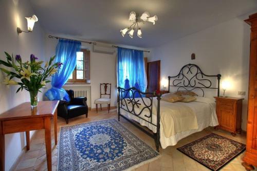 a bedroom with a bed with blue curtains and a chair at Villas Angiolina in Višnjan