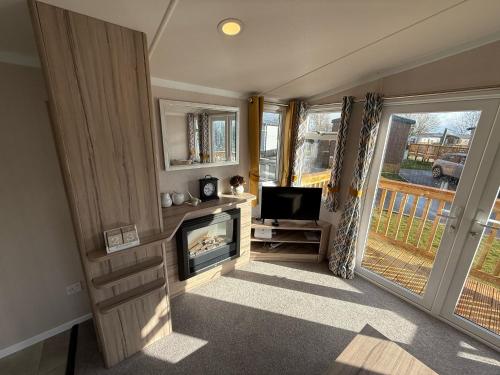 a living room with a fireplace and a television at Starling Lodge with Hot tub at Brickyard Lakes in Amotherby