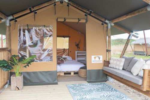 a tent with a bed and a couch in it at TinyParks Eiland Tiengemeten in Zuid-Beijerland