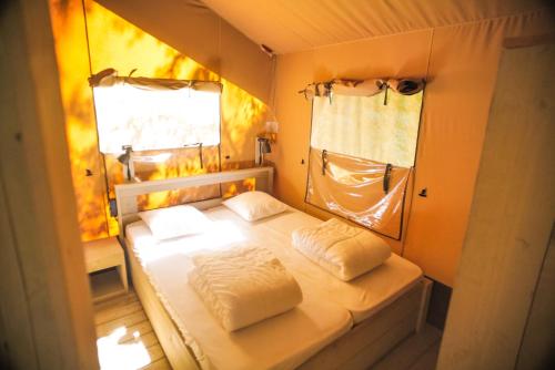 un petit lit dans une chambre avec une fenêtre dans l'établissement Camping Domaine le Peyral - Pionier Lodge XL, à La Salvetat-sur-Agout