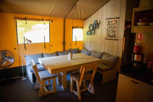 une salle à manger avec une table, des chaises et un canapé dans l'établissement Camping Domaine le Peyral - Pionier Lodge XL, à La Salvetat-sur-Agout