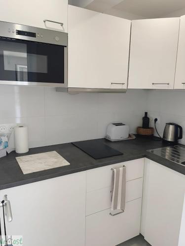 une cuisine blanche avec des armoires blanches et un micro-ondes dans l'établissement Devalois Versailles - CI - Le Devalois Paisible logement près du Château, à Le Chesnay