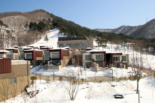 a building in the snow with a mountain in the background at Pyeongchang Space hubt Hotel & Resort in Pyeongchang 
