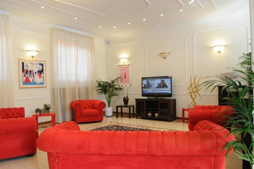 sala de estar con muebles de color rojo y TV de pantalla plana en Hotel Riviera Varazze en Varazze