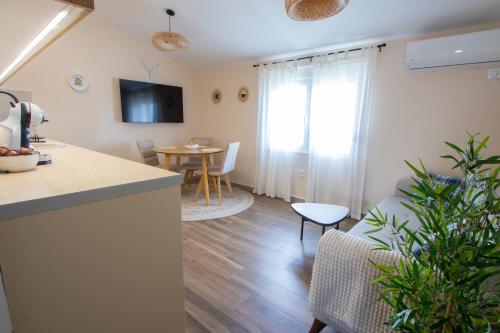 a kitchen and a living room with a table at Bright & Cozy Apartment in quiet area near Airport in Golubovci