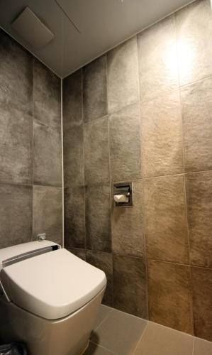 a bathroom with a toilet and a tiled wall at Pyeongchang Space hubt Hotel & Resort in Pyeongchang 