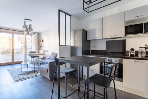 une cuisine avec des armoires blanches et une table et des chaises dans l'établissement Charmant appartement proche de Paris, à Vincennes