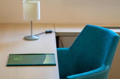 a blue chair sitting next to a table with a laptop at Hotel Kiss in Tata