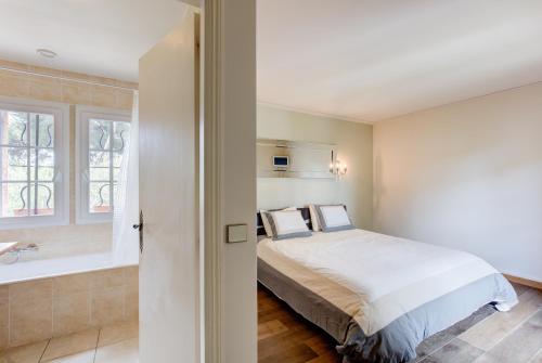 - une chambre avec un lit et une baignoire à côté d'une fenêtre dans l'établissement Villa in Antibes domain with tennis and pools, à Antibes
