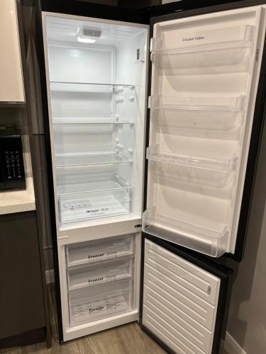 an empty refrigerator with its door open in a kitchen at Spacious 3 Bed Home - Ideal for Families & Groups in Stanford le Hope
