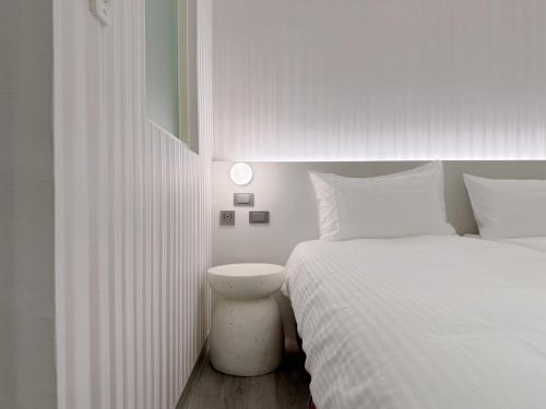 a white bedroom with two beds and a night stand at 在家行旅 南西館 in Taipei