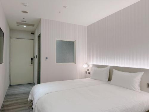 a white bedroom with a large bed with white pillows at 在家行旅 南西館 in Taipei
