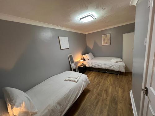 a bedroom with two beds and a lamp in it at Spacious 3 Bed Home - Ideal for Families & Groups in Stanford le Hope