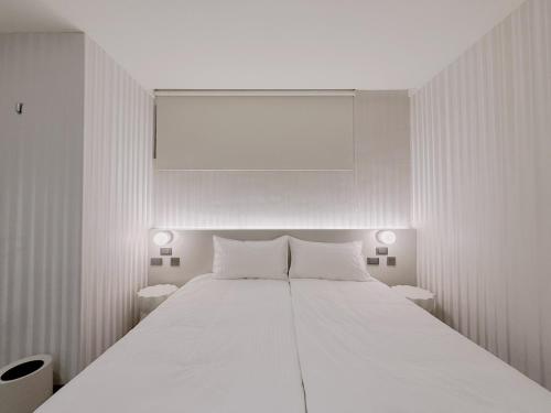 a white bedroom with a large white bed with two tables at 在家行旅 南西館 in Taipei